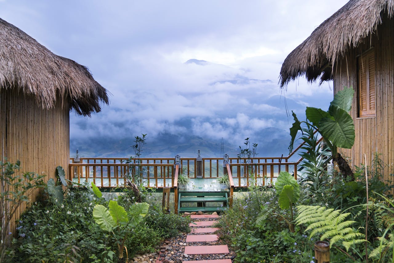 gallery-6 Bamboo huts overlooking lush gardens and misty mountains create a serene escape.