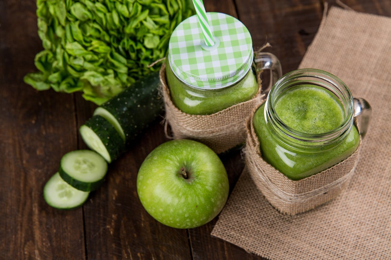 hero-img-02 Refreshing green smoothie made with apple, cucumber, and lettuce served in mason jars on wooden background.