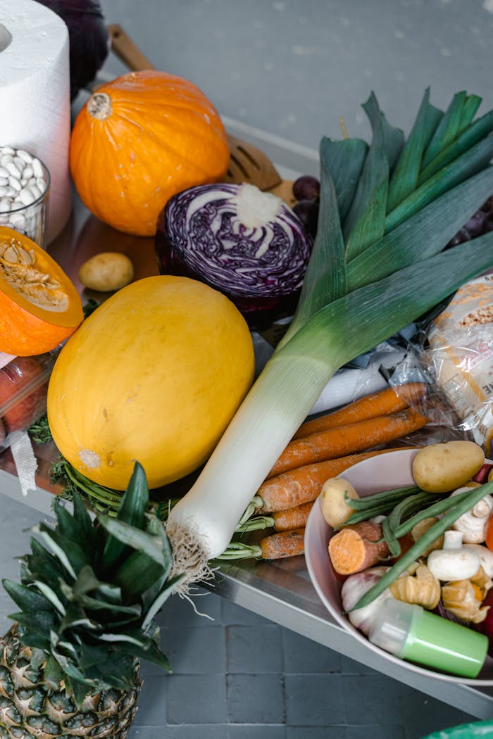 gallery-2 A vibrant arrangement of assorted fresh vegetables including squash, leek, and carrots on a stainless steel counter.