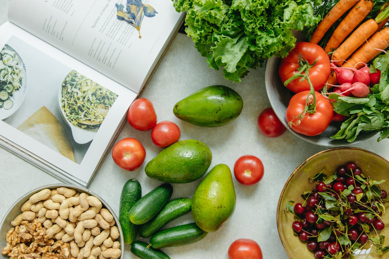 our-services-2 An appetizing display of fresh fruits and vegetables with a cookbook, perfect for healthy recipes.